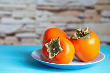 Wall Mural - Persimmon on blue plate against background of stone wall