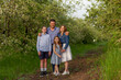 © Daria - Beautiful family walking outdoors among the blossom apple trees. Happy group of four enjoying time with fresh nature together. Mood concept