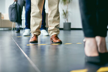 Close-up Of Business People Standing In A Row Behind Social Distance Lines At Office Building.