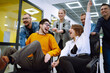 © maxbelchenko - Young colleagues group having fun together, riding on chairs in office, diverse excited office workers enjoying break, laughing, engaged funny activity, celebrating corporate success.