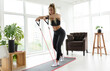 Woman during her fitness workout at home with rubber resistance band.