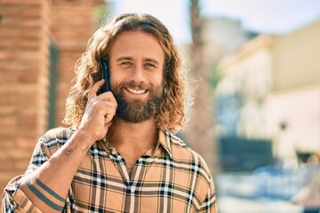 Wall Mural - Young caucasian man smiling happy talking on the smartphone at the city.