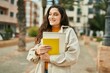 © Krakenimages.com - Young middle east student woman smiling happy holding book at the city.