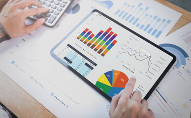 Businesswoman using a tablet to analysis graph company finance strategy statistics success concept and planning for future in office room.