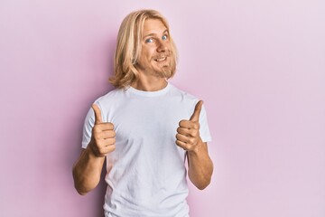 Sticker - Caucasian young man with long hair wearing casual white t shirt success sign doing positive gesture with hand, thumbs up smiling and happy. cheerful expression and winner gesture.