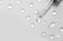 Cosmetic Liquid Dropper With Bubbles Top View. Transparent Clear Liquid Serum Gel In Pipette. Many Drops On Gray Background And Copy Space.