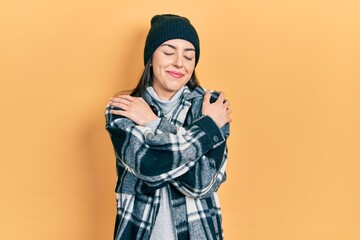 Poster - beautiful woman with blue eyes wearing wool cap hugging oneself happy and positive, smiling confiden