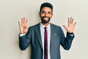 Sticker - Handsome hispanic man with beard wearing business suit and tie showing and pointing up with fingers number nine while smiling confident and happy.