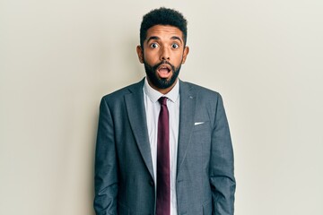 Wall Mural - Handsome hispanic man with beard wearing business suit and tie afraid and shocked with surprise and amazed expression, fear and excited face.