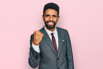 Wall Mural - Young african american man wearing business clothes angry and mad raising fist frustrated and furious while shouting with anger. rage and aggressive concept.