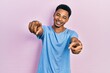 © Krakenimages.com - Young african american man wearing casual blue t shirt pointing to you and the camera with fingers, smiling positive and cheerful