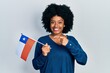 © Krakenimages.com - Young african american woman holding chile flag smiling happy pointing with hand and finger