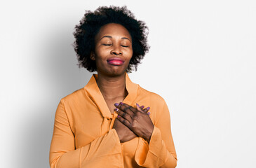 Wall Mural - African american woman with afro hair wearing elegant shirt smiling with hands on chest with closed eyes and grateful gesture on face. health concept.