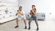 © Prostock-studio - Fit black couple in sportswear doing squat exercises at home gym during covid, panorama