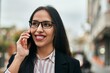 © Krakenimages.com - Young hispanic businesswoman smiling happy talking on the smartphone at the city.