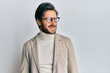 © Krakenimages.com - Young hispanic man wearing business jacket and glasses looking away to side with smile on face, natural expression. laughing confident.