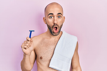 Sticker - Young bald man shirtless holding razor scared and amazed with open mouth for surprise, disbelief face