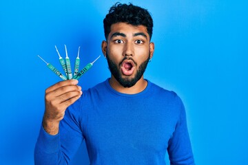 Poster - Arab man with beard holding picklock to unlock security door scared and amazed with open mouth for surprise, disbelief face