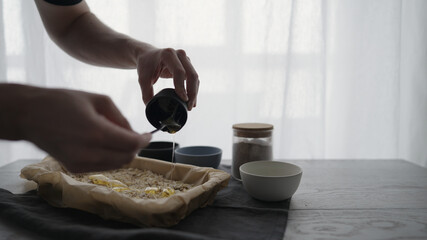 Wall Mural - Man making homemade granola with honey and different flakes on oak table