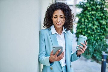 Young hispanic business woman wearing professional look smiling confident at the city using smartphone