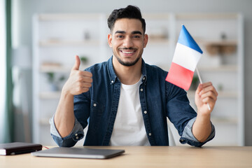 Smiling guy with flag of France and showing thumb up