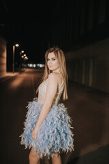 Poster - Attractive female posing in a blue dress with feathers outdoor in the evening