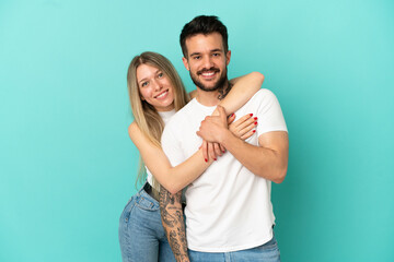 Wall Mural - Young couple over isolated blue background laughing and hugging