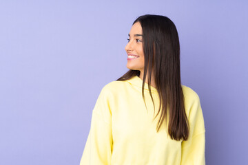 Wall Mural - Young caucasian woman over isolated background looking to the side and smiling