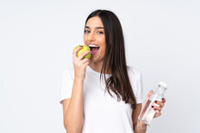 Young Caucasian Woman Isolated On White Background With A Bottle Of Water And Eating An Apple