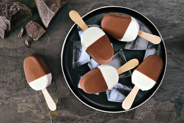 Poster - Plate of chocolate dipped vanilla ice cream bars. Top view over a dark slate background.