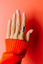 Woman's Hand In Red Sweater And Big Beautiful Silver Ring On Finger, Vertical Frame On Red Background