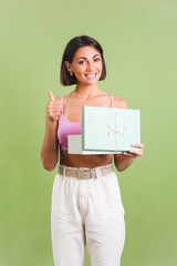 Woman in pink crop top and white trousers on green background holding gift box happy positive excited cheerful posing