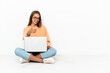 © luismolinero - Young woman with a laptop sitting on the floor with thumbs up because something good has happened