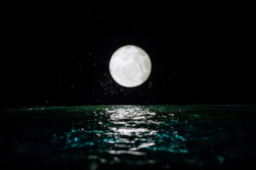Wall Mural - Romantic and scenic panorama with full moon on sea to night. Table decoration with moon miniature and water.