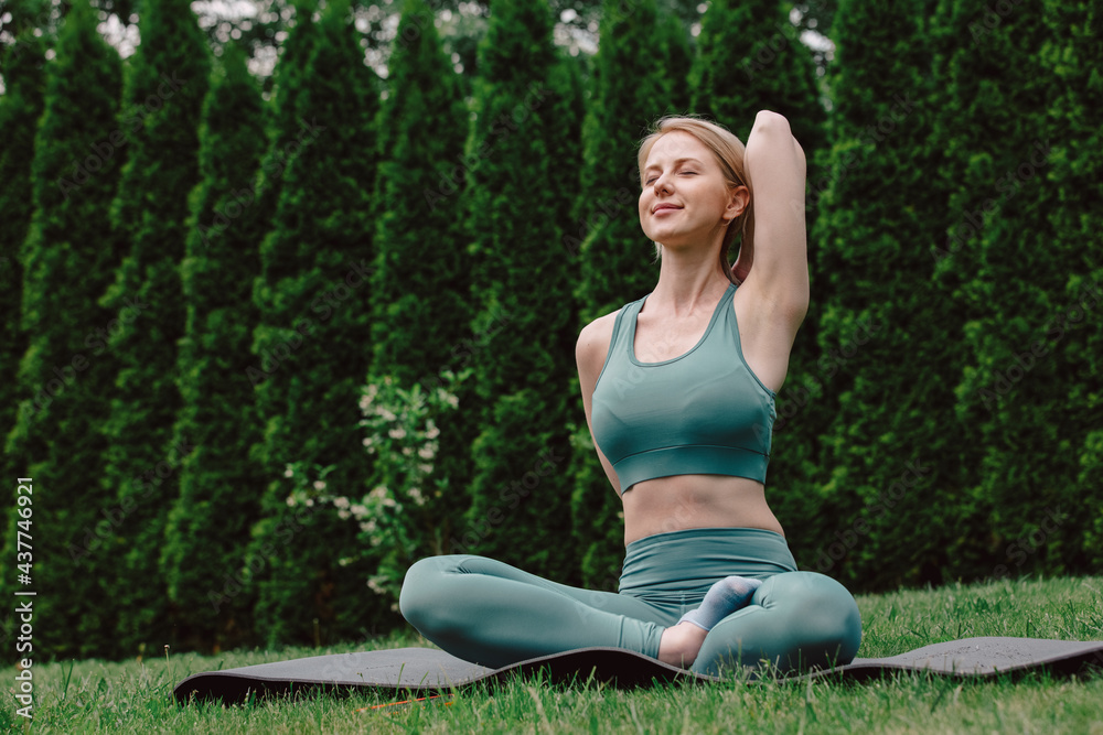 young woman practicing yoga on the grass in the garden - obrazy, fototapety, plakaty 