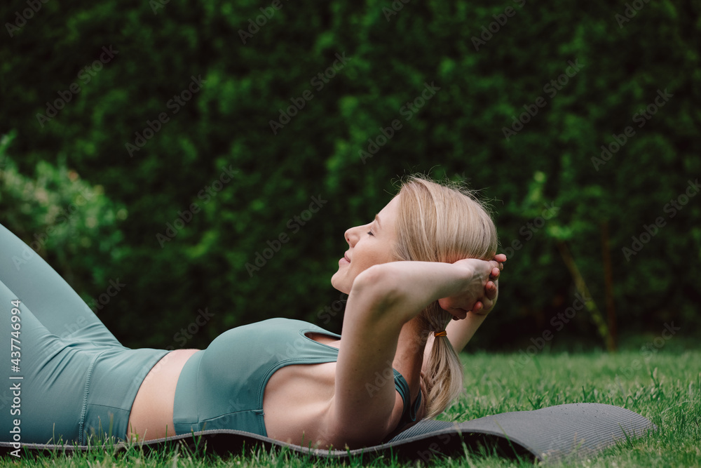 young woman practicing yoga on the grass in the garden - obrazy, fototapety, plakaty 