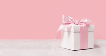 White Gift Box With Shining Pink Ribbon Bow On Pink Background. Gift Or Holiday Concept. Mothers Day, Birthday Wedding Or St Valentines Day Banner With Copy Space