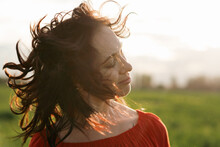beautiful hispanic young woman in red dress dancing in a field at sunset