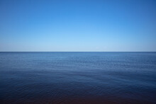 A Calm Blue Lake Against A Clear Sky With A Horizon And A Space For Text.