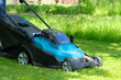Garden electric lawn mower cutting grass, closeup view.