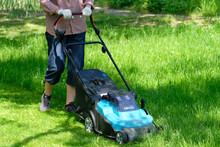 Woman Using Electric Lawn Mower For Cutting Grass.