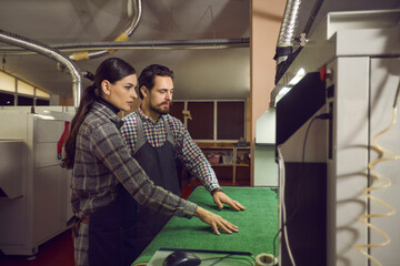 two shoe factory workers checking the work of a cutting machine at a manufacturing workshop. concept