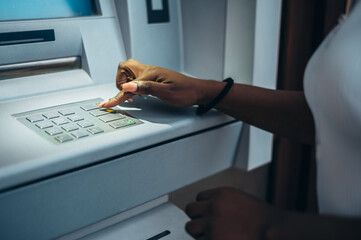 Wall Mural - African american woman typing pin code and withdrawing cash at the ATM