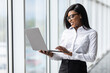 © F8  \ Suport Ukraine - Beautiful young woman with a laptop in modern office. African american businesswoman standing by a railing in office