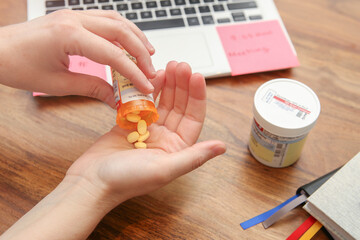 Winnipeg, Manitoba - Canada - June 5, 2021: Close-up of Hand Holding Pills. Minimalist Home Office Background.