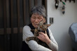 Portrait of an old Asian lady holding a brown patch cat in Japan.
