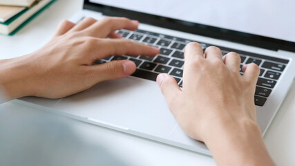 Close up of man hand typing laptop computer while working at home office, Student college online study, learning, people and technology