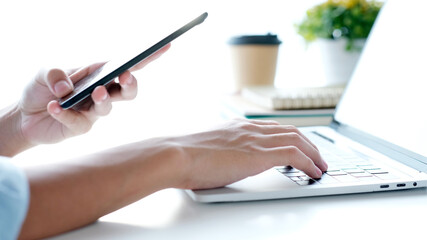 Wall Mural - close up of man hand holding mobile phone and typing laptop computer whie working at home office, st