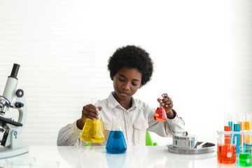 african american cute little boy student child learning research and doing a chemical experiment whi