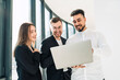 © Andrii  - Cheerful company workers look into a laptop and laugh